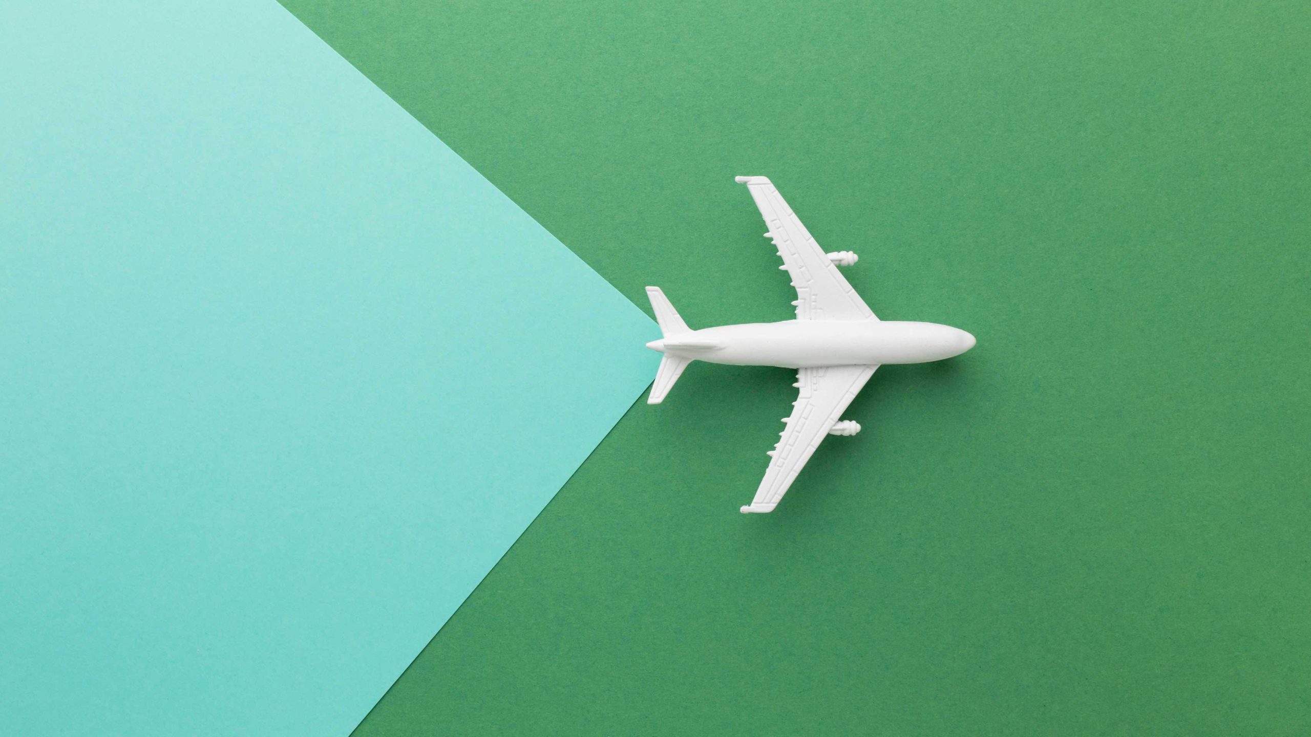 top-view-white-plane-on-green-background-1-scaled